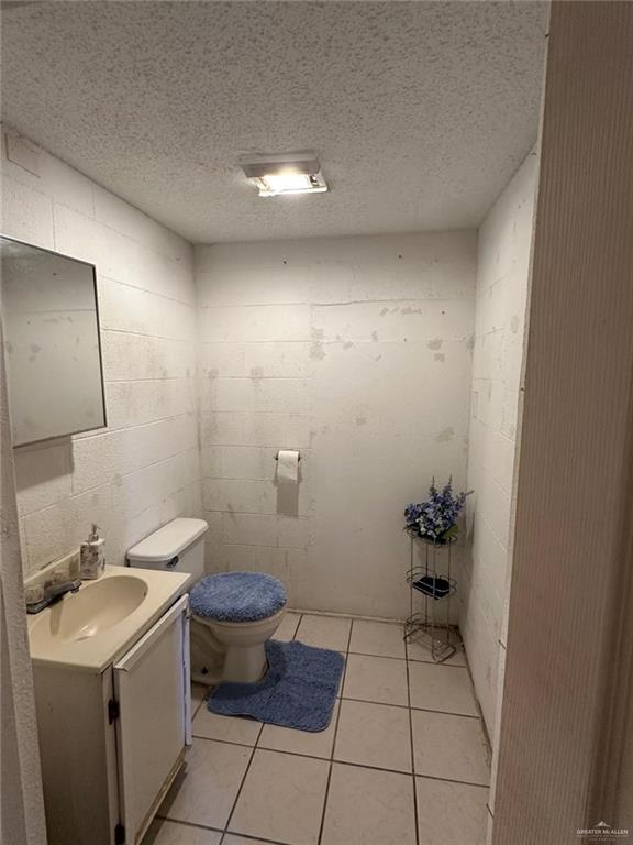 bathroom with toilet, a textured ceiling, and tile patterned floors