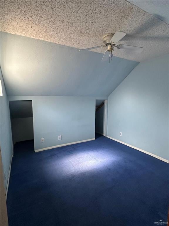 bonus room with vaulted ceiling, ceiling fan, a textured ceiling, and dark colored carpet