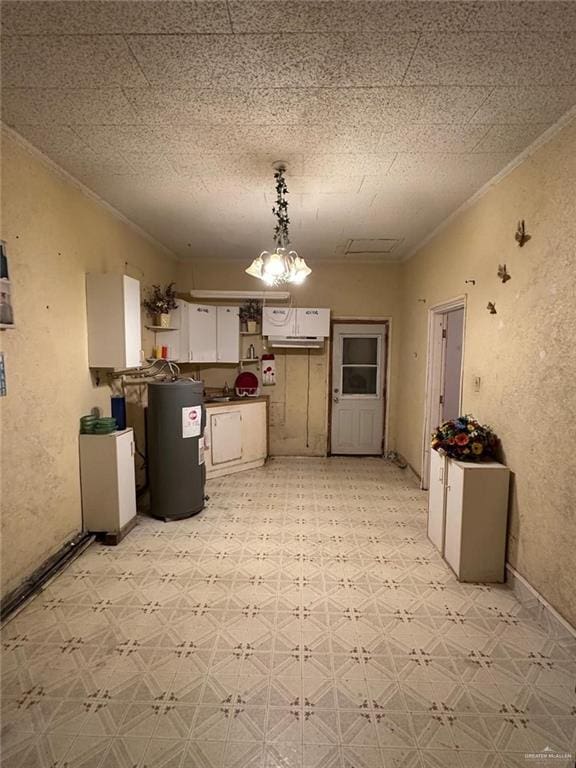 kitchen featuring white cabinetry, water heater, a notable chandelier, pendant lighting, and ornamental molding