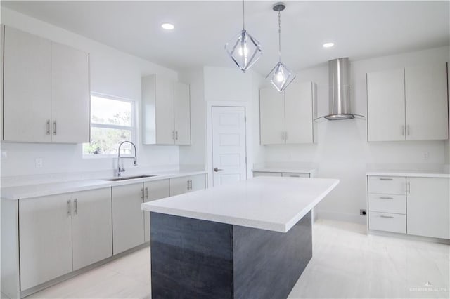 kitchen with a center island, white cabinets, sink, and wall chimney exhaust hood