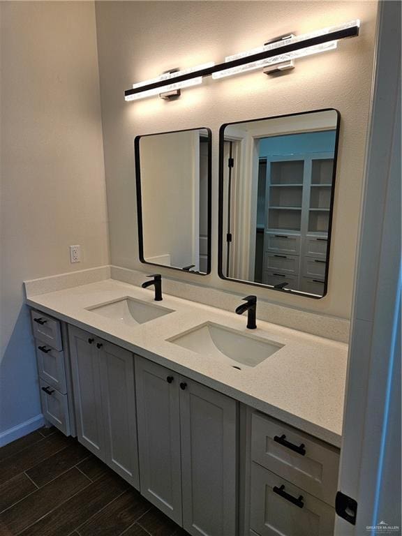 full bathroom featuring double vanity, wood finished floors, and baseboards