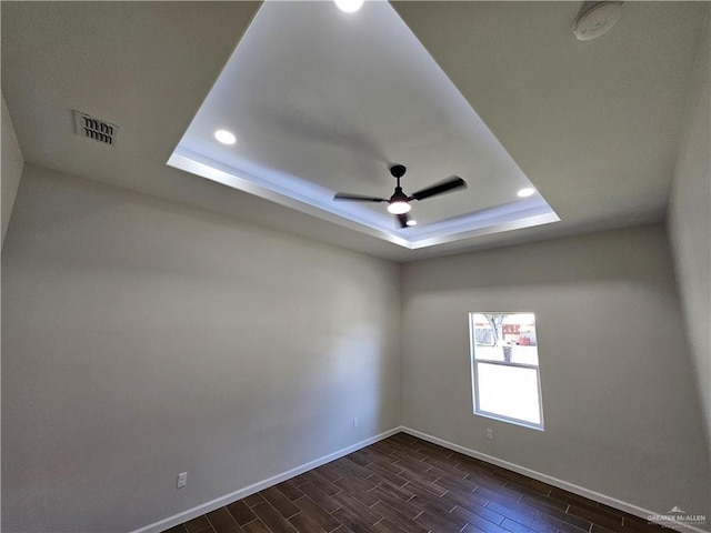 unfurnished room with a tray ceiling, wood finish floors, baseboards, ceiling fan, and recessed lighting