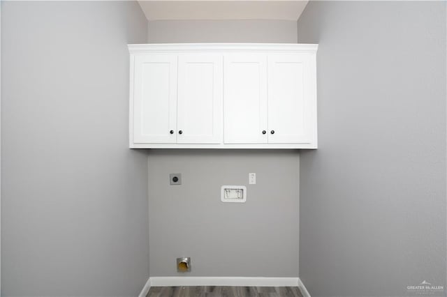 laundry room with electric dryer hookup, dark hardwood / wood-style flooring, and cabinets