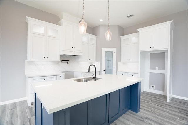 kitchen with white cabinetry, sink, and a kitchen island with sink