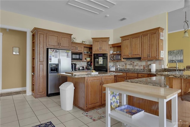 kitchen featuring backsplash, light stone counters, black appliances, light tile patterned floors, and a center island