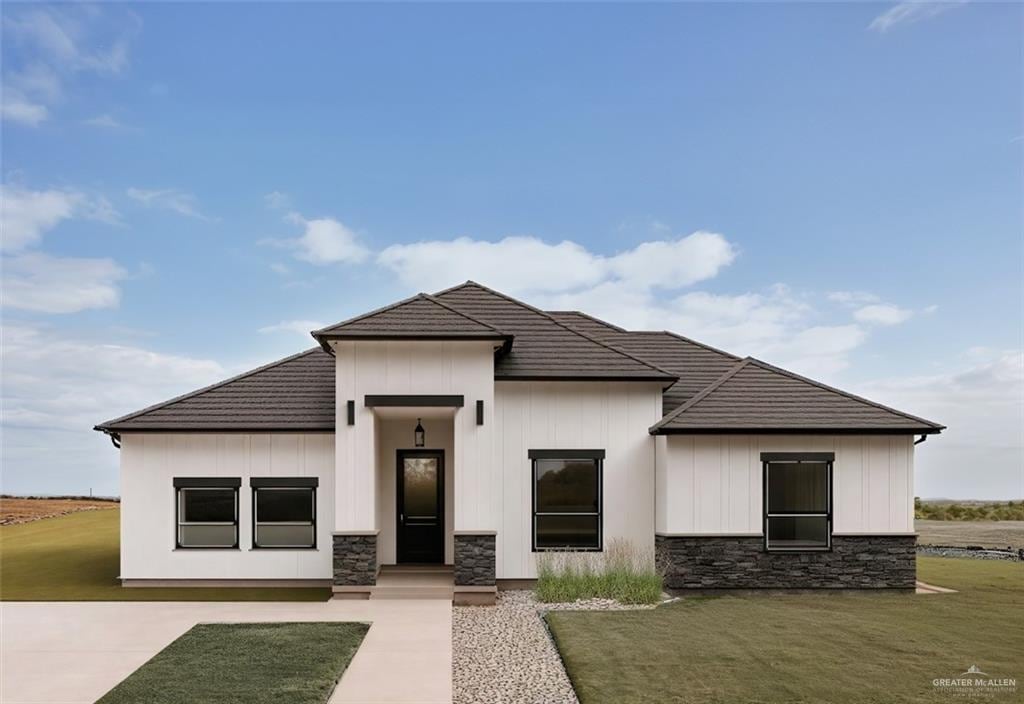 109 Lenon St, Edcouch, TX 78538 - view of front of house with stone siding, a front yard, a tile roof, and board and batten siding