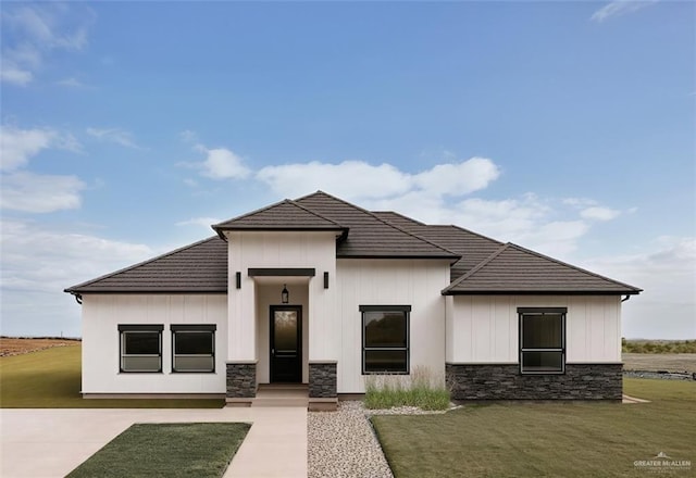 109 Lenon St, Edcouch, TX 78538 - view of front of house with stone siding, a front yard, a tile roof, and board and batten siding