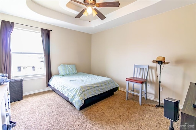 bedroom featuring ceiling fan, light carpet, and a tray ceiling