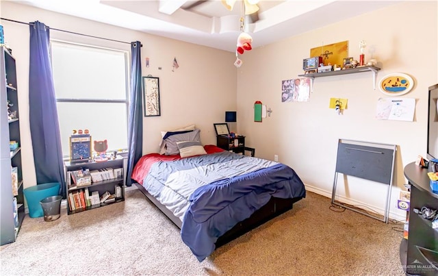 carpeted bedroom with ceiling fan and a raised ceiling