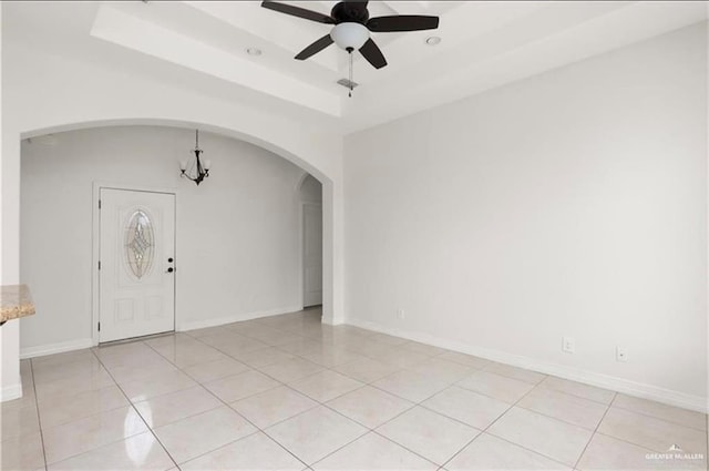 foyer entrance featuring light tile patterned floors, ceiling fan with notable chandelier, and a tray ceiling