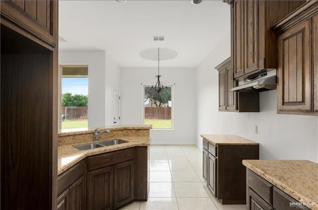 kitchen with light stone countertops, dark brown cabinets, sink, pendant lighting, and light tile patterned flooring