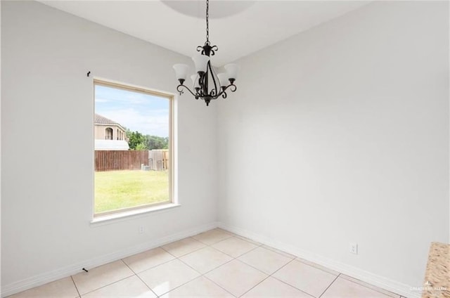 spare room featuring a chandelier, light tile patterned flooring, and a healthy amount of sunlight