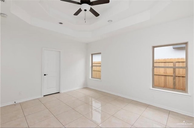 tiled spare room with a raised ceiling and ceiling fan