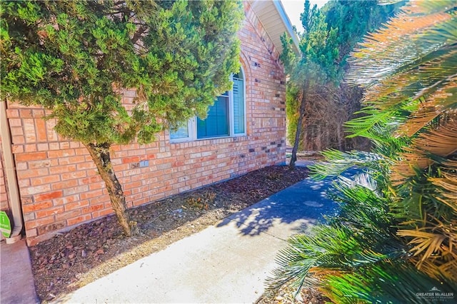 view of side of property featuring brick siding and fence