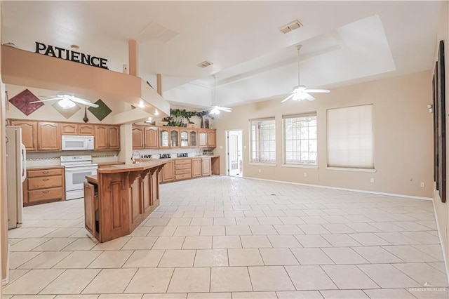 kitchen featuring ceiling fan, white appliances, a kitchen breakfast bar, open floor plan, and a tray ceiling