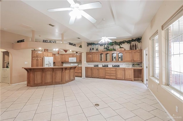 kitchen featuring light countertops, visible vents, glass insert cabinets, white appliances, and a kitchen bar