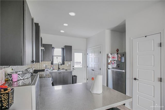 kitchen with backsplash, a sink, freestanding refrigerator, a peninsula, and recessed lighting