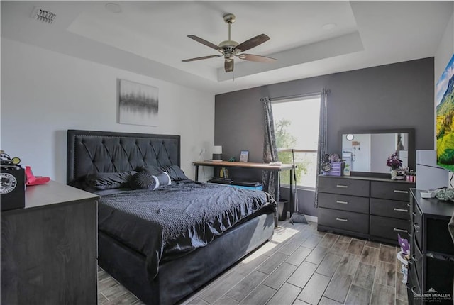 bedroom featuring baseboards, wood tiled floor, and a tray ceiling