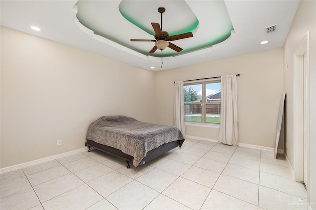 bedroom with a tray ceiling, visible vents, baseboards, and light tile patterned floors