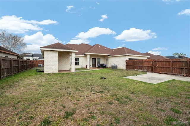 back of house with a patio area, a fenced backyard, brick siding, and a yard