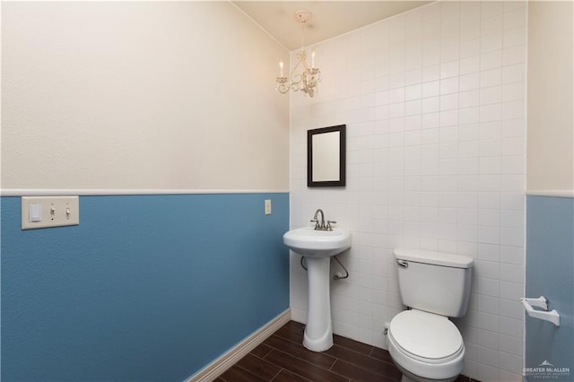 701 S Parker Rd S, La Feria, TX 78559 - bathroom featuring wood finish floors, a chandelier, toilet, tile walls, and a sink
