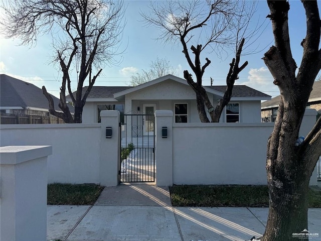 ranch-style home featuring a fenced front yard, a gate, and stucco siding