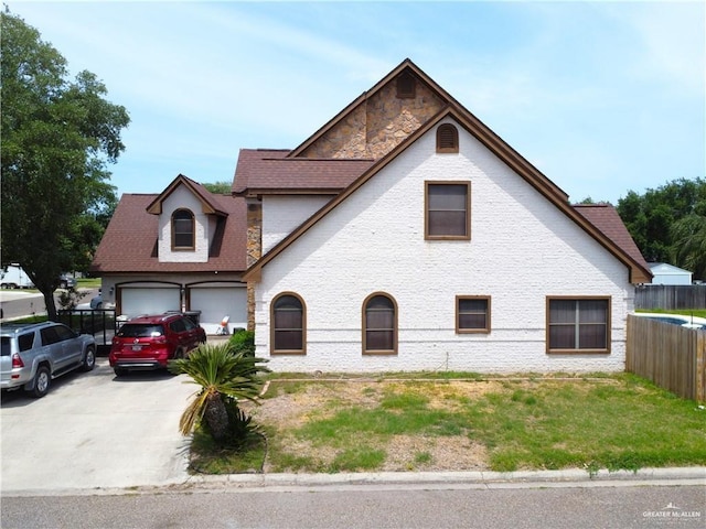 2206 Highland Dr, Weslaco, TX 78599 - view of front of home featuring driveway, fence, roof with shingles, and stone siding