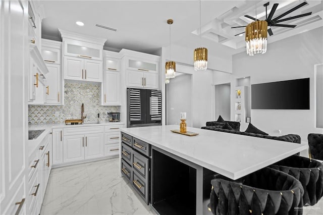 kitchen with hanging light fixtures, white cabinetry, a breakfast bar, and sink