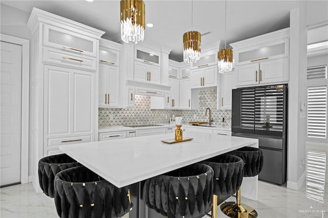 kitchen with a breakfast bar, refrigerator, white cabinets, cooktop, and an inviting chandelier