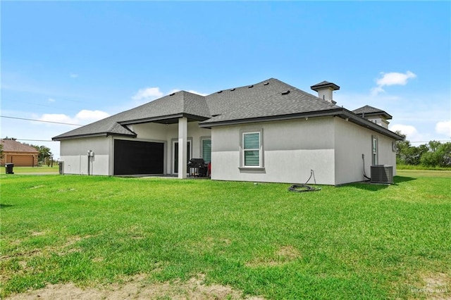 rear view of house with a garage, a lawn, and central air condition unit