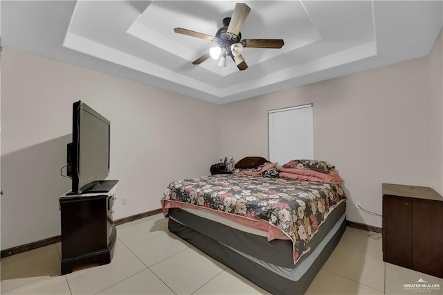 bedroom with light tile patterned flooring, a ceiling fan, a raised ceiling, and baseboards