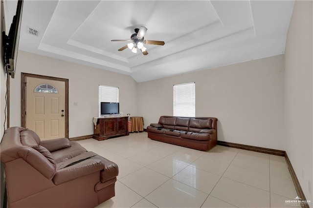 living area featuring visible vents, a raised ceiling, a ceiling fan, light tile patterned floors, and baseboards