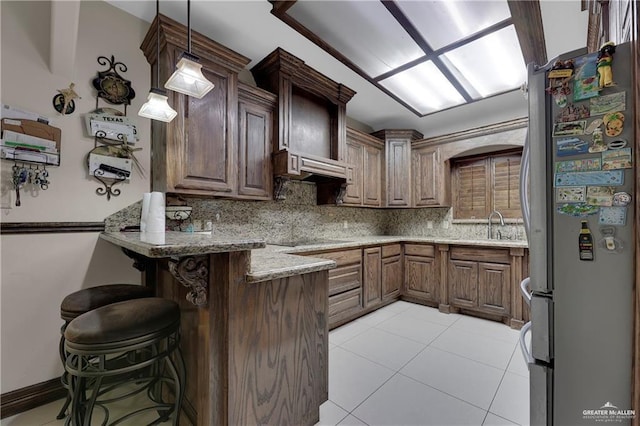 kitchen featuring black electric cooktop, tasteful backsplash, a peninsula, and freestanding refrigerator