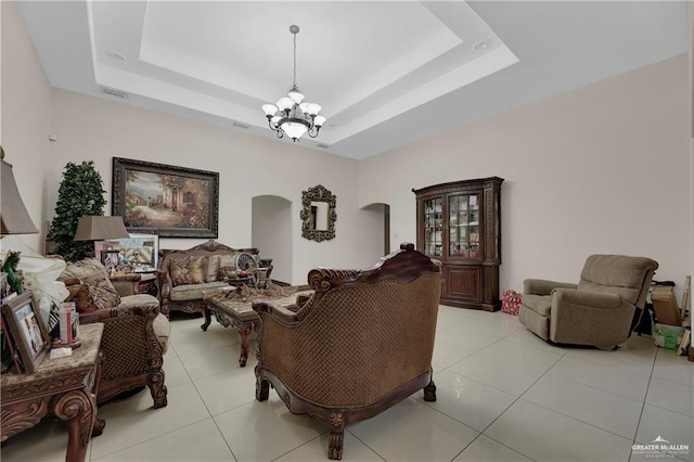 living area featuring arched walkways, visible vents, a raised ceiling, and light tile patterned flooring