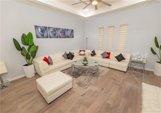 living area featuring recessed lighting, wood finished floors, a ceiling fan, baseboards, and a raised ceiling