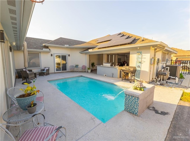 exterior space featuring outdoor dry bar, stucco siding, roof mounted solar panels, a patio area, and an outdoor pool