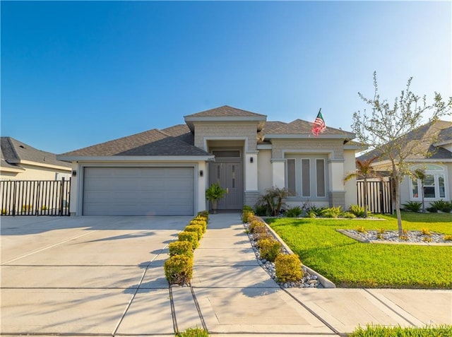 prairie-style home featuring concrete driveway, a front lawn, an attached garage, and fence