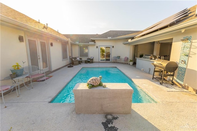 outdoor pool with french doors, a patio area, and area for grilling