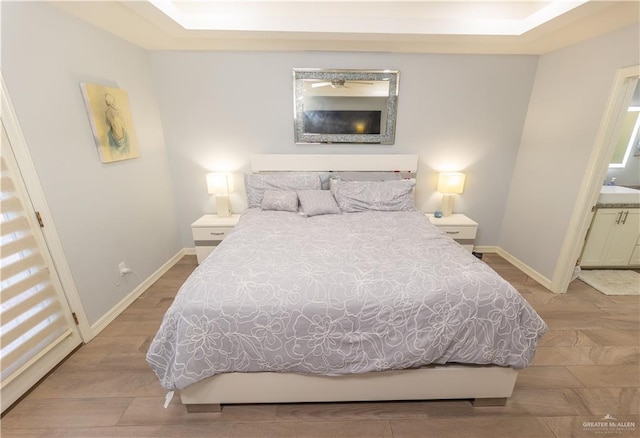 bedroom featuring wood finished floors, connected bathroom, and baseboards