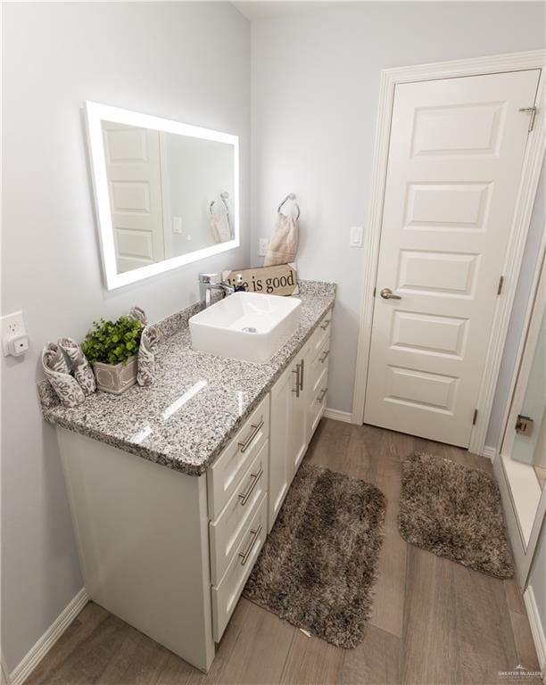 bathroom featuring vanity, baseboards, and wood finished floors