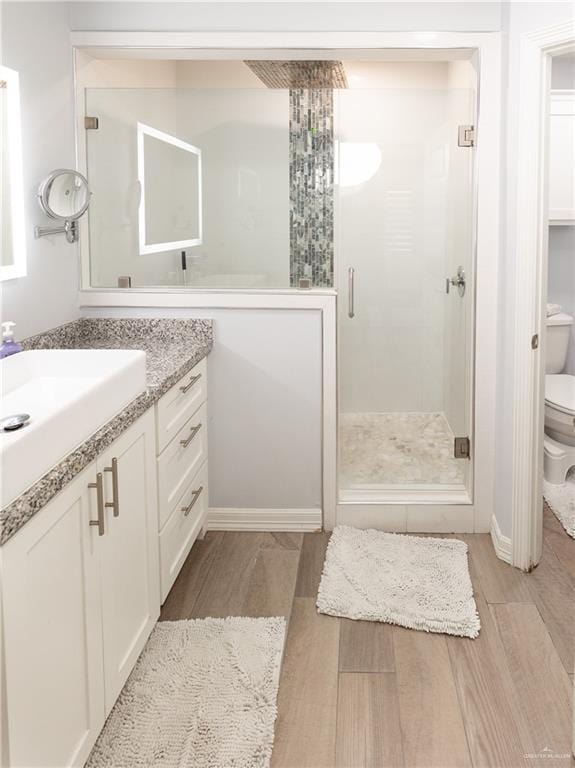 full bath with toilet, a stall shower, wood finished floors, and vanity