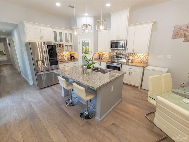 kitchen featuring stainless steel appliances, white cabinetry, a sink, and light wood finished floors