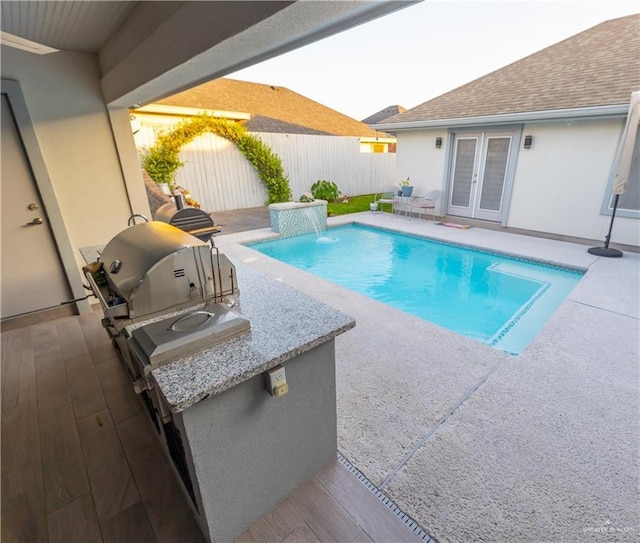 view of pool with a fenced in pool, french doors, an outdoor kitchen, a patio area, and fence