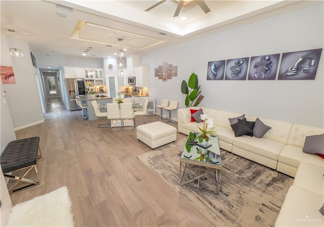 living room featuring recessed lighting, a ceiling fan, visible vents, light wood finished floors, and a raised ceiling