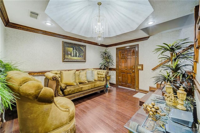 living room with hardwood / wood-style floors, an inviting chandelier, and ornamental molding