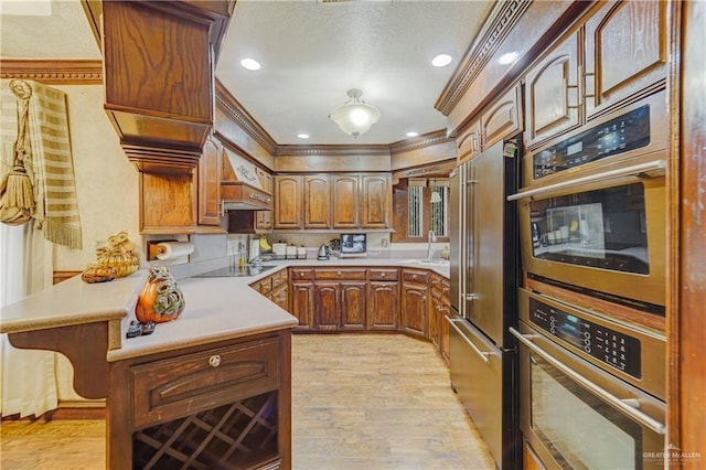 kitchen featuring kitchen peninsula, high end refrigerator, light wood-type flooring, black electric cooktop, and crown molding