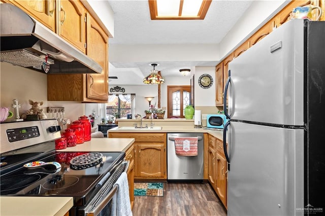 kitchen featuring appliances with stainless steel finishes, a textured ceiling, sink, dark hardwood / wood-style floors, and hanging light fixtures