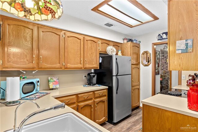 kitchen with stainless steel fridge, cooktop, and light hardwood / wood-style flooring