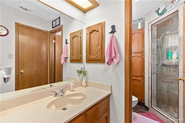 bathroom with vanity, toilet, and a shower with shower door