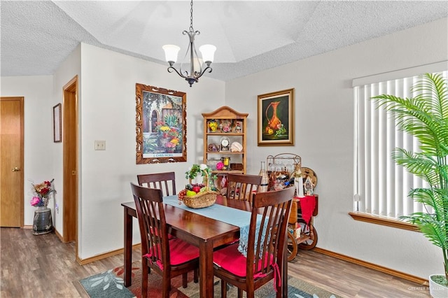 dining room featuring wood-type flooring, a textured ceiling, and a notable chandelier